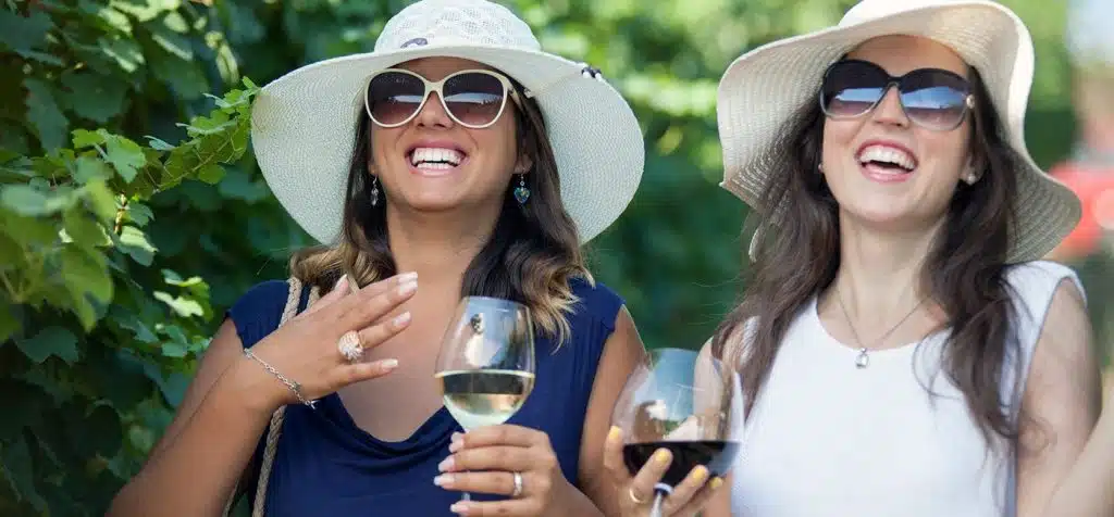 women laughing while drinking wine e1693934444383